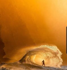 a man standing on top of a surfboard in the ocean next to a large wave