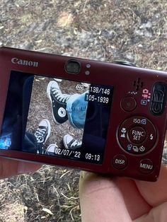 a person holding up a camera to take a picture with their feet on the ground