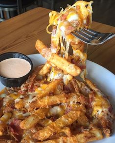 a white plate topped with cheesy fries and sauce