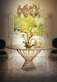 a glass table with flowers on it in front of an open door and chandelier