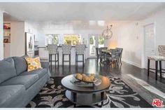 a living room filled with furniture next to a dining room table and bar stools