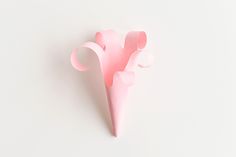 a pink paper sculpture on a white surface with the shape of a flower in the center