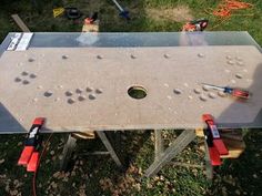 a metal table with holes in it and tools attached to the top that is being worked on