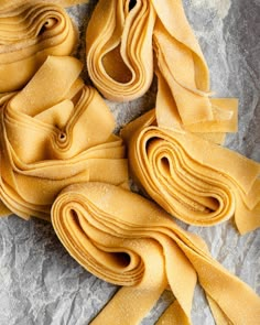 several pieces of uncooked pasta sit on a piece of wax paper, which has been rolled up to look like spirals