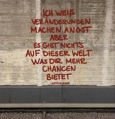 graffiti on the side of a building with words written in red and black, against a white brick wall