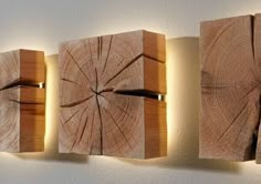 three pieces of wood are mounted to the wall with lights on each side and one piece has been cut in half