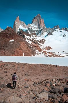 a man hiking up the side of a mountain with snow on it's mountainside