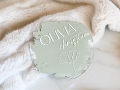 a round sign that says ohma christmas on it next to a pile of blankets