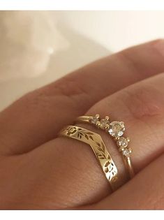 a woman's hand with two gold rings on top of her finger and the other ring