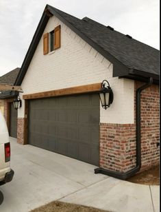 a white van is parked in front of a brick and stone house with two garage doors