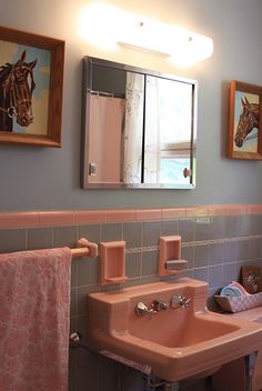 a pink sink in a bathroom next to a mirror and towels hanging on the wall