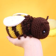 a hand holding a small crocheted stuffed animal with a bee on it's back