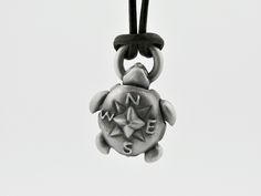 a small metal turtle is hanging from a chain on a white background and has the word nn e written in it's upper corner