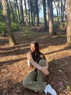 a woman sitting on the ground in front of trees