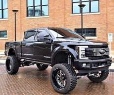 a large black truck parked in front of a brick building