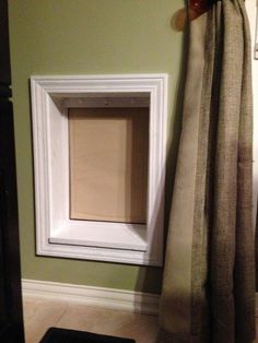 a cat door is open in the corner of a room with green walls and white trim