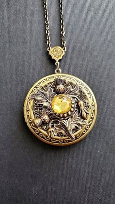 Large Flower Locket Necklace This necklace locket is bronze and copper, decorated with beautiful thistle flower that gives a vintage style cottage vibe. The piece is very involved and carefully made with a lot of detail. A lovely locket Necklace showcasing a yellow stone. See Photos for size comparison against American quarter Chain: ~ Antique Bronze Choose YOUR CHAIN LENGTH during checkout ☻More Lockets Here: https://www.etsy.com/shop/FashionCrashJewelry/search?search_query=lockets&order=date_d Luxury Vintage Round Pendant Locket Necklace, Antique Copper Locket Jewelry, Antique Gold Steampunk Jewelry As Gift, Antique Gold Steampunk Jewelry Gift, Antique Gold Steampunk Jewelry For Gift, Steampunk Antique Gold Jewelry Gift, Steampunk Medallion Engraved Jewelry, Steampunk Gold Jewelry With Antique Finish, Bronze Steampunk Jewelry With Engraving