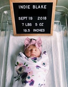 a newborn baby wrapped in a blanket with a sign above it that says india blake