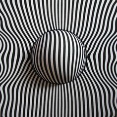 an abstract black and white striped object with a ball on it's back end