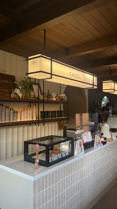 a counter with food on it in front of some shelves and lights hanging from the ceiling