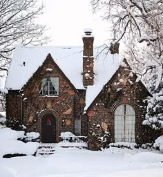 a brick house covered in snow next to trees