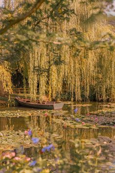 a boat floating on top of a lake next to a forest filled with green leaves