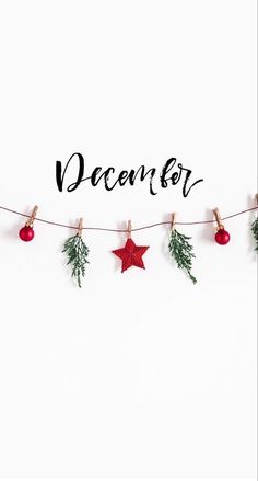 the word december is written on a white background with christmas decorations hanging from clothes pins