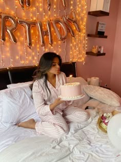 a woman sitting on a bed holding a cake