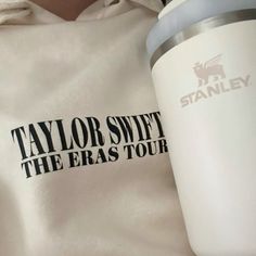 taylor swift the era tour logo on a white hoodie next to a coffee cup