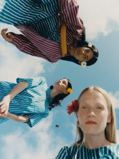 three women are standing in the air with their heads tilted to the side and looking up at the sky