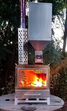 a stove that is sitting on top of a wooden table in the middle of some trees