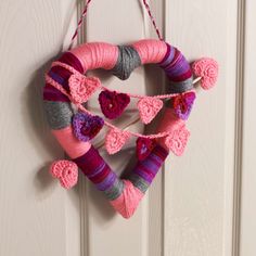 a crocheted heart hanging on a door with yarn balls and hearts attached to it