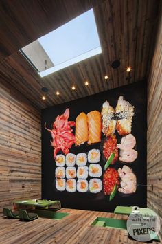 sushi is displayed in front of a large poster on the wall above it's counter