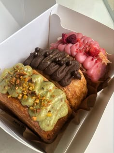 an open box filled with assorted pastries and desserts on top of each other