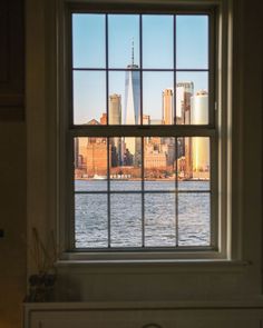 a window with a view of the water and buildings in new york city from across the river