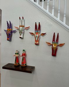 several colorfully painted wooden figurines are displayed on a wall next to a banister