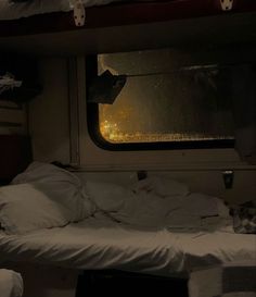 there is a bed with white sheets and pillows on the floor next to a window