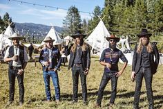 five men with long hair and beards standing in front of teepee tents at an outdoor event