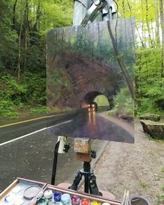 an artist is painting in the woods with his easel