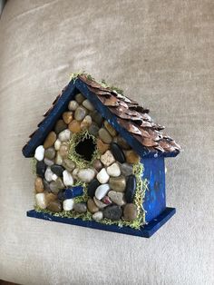 a birdhouse made out of rocks and grass on top of a bed with a pillow