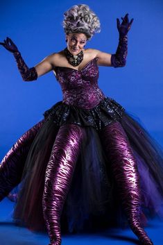 a woman dressed in purple and black with her legs spread out, posing for the camera