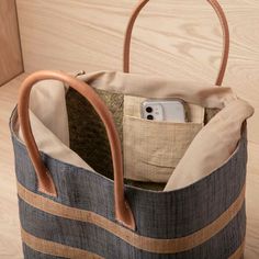 an open bag sitting on top of a wooden floor next to a cell phone in it