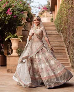 a woman in a white and gold bridal gown walking down the stairs with her hand on her hip