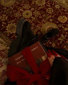 a pair of black shoes sitting on top of a red blanket next to a book