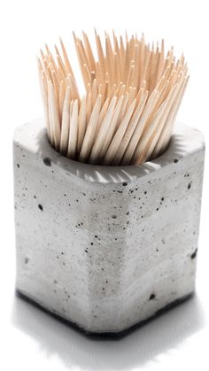 a toothbrush holder with wooden sticks sticking out of it's sides on a white background