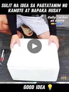 a person holding a white box on top of a wooden table next to a knife