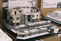 a model of a house on display in a room with other models and papers around it