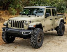 a tan jeep is parked in the dirt