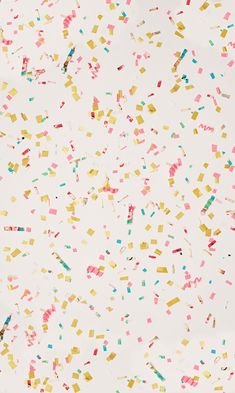 colorful confetti sprinkles are scattered on a white surface with no background