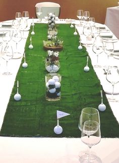 a long table is set up with wine glasses and golf balls on the green grass